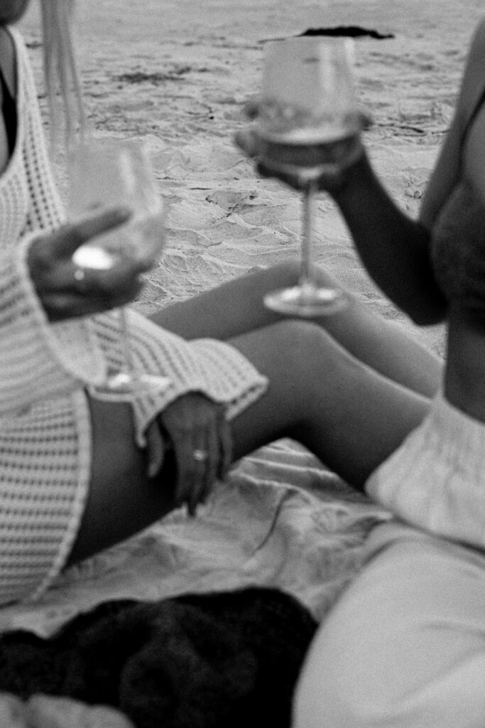 two friends share a glass of wine on the beach 